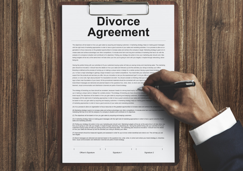 A hand signing a divorce agreement